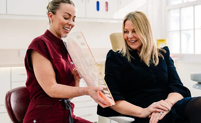 A dentist showing a patient tooth options during a cosmetic consultation