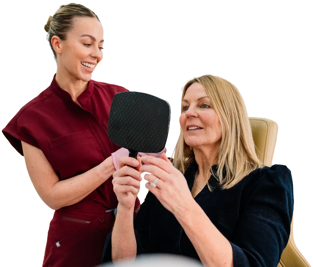 A clinician holding a mirror for a patient during a facial aesthetics consultation